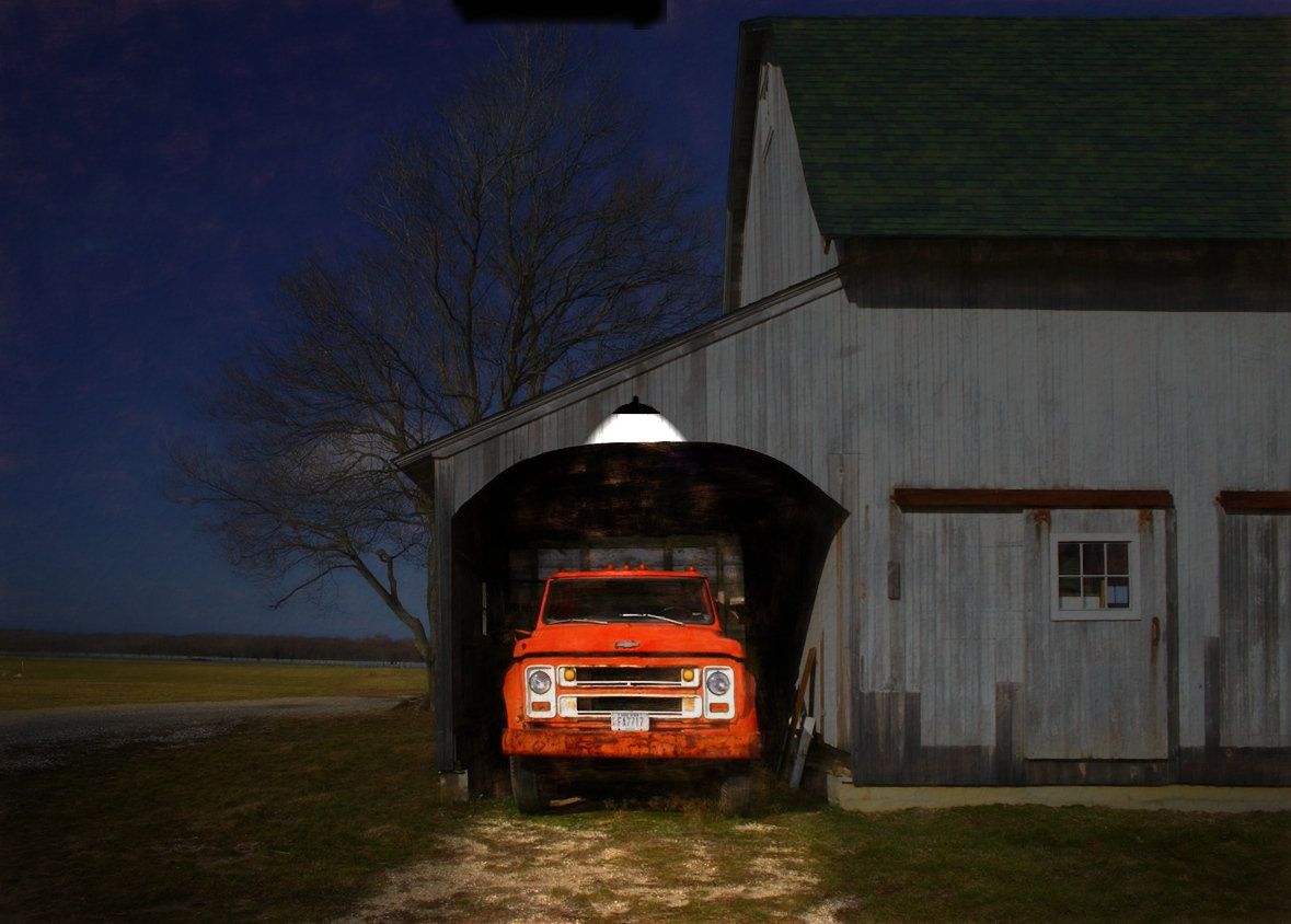A red truck is illuminated by a single light on this barn in Hallockville, NY