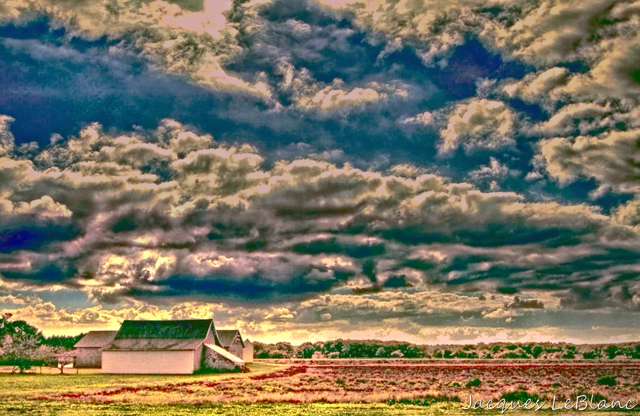 Sunset lit clouds dominate the sky over a Riverhead farm that has a barn with a green colored roof. 